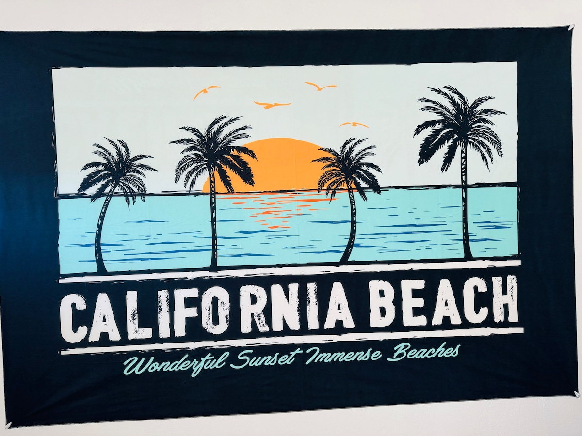 A decorative wall tapestry features a stylized beach scene with silhouettes of palm trees against a sunset. The image is framed by a gradient of orange and blue, with the text 'CALIFORNIA BEACH' prominently displayed at the bottom.