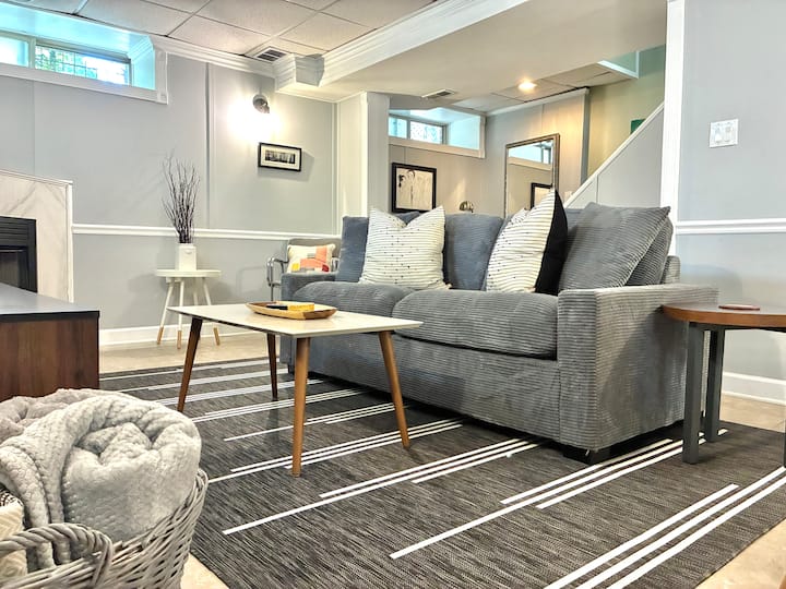 غرفة معيشة مريحة مجهزة بالألعاب ووحدة تحكم في الألعاب وتلفزيون ذكي وأريكة نوم قابلة للسحب بحجم كوين.