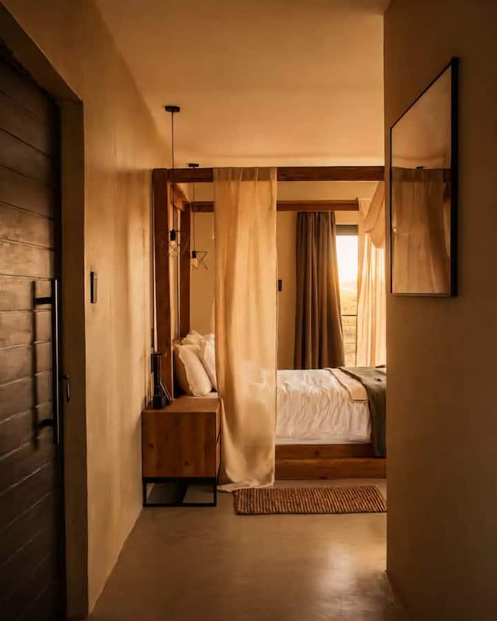 Suite Nyati - dormitorio principal con baño de planta abierta, balcón, chimenea