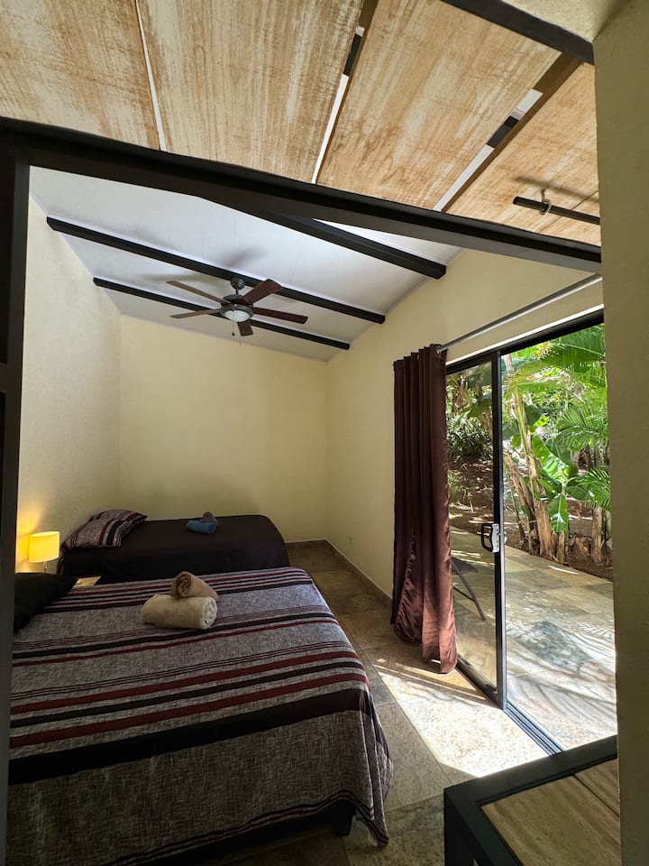 Chambre confortable équipée de deux lits doubles, avec salle de bain privée, climatisation et vue sur la piscine.
