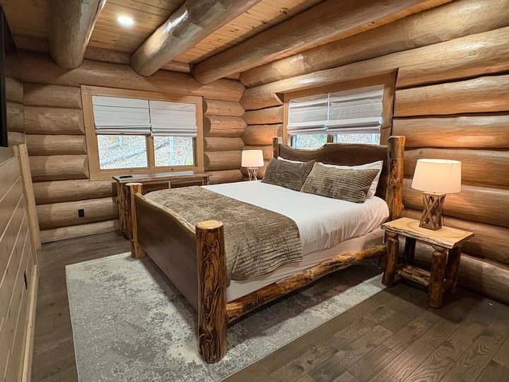 The first-floor master suite is a private, luxurious retreat featuring a king-size bed, premium linens, and warm cabin charm. Enjoy a walk-in closet, a private ensuite bathroom, and a flat-screen smart TV, perfect for unwinding after a summer day.