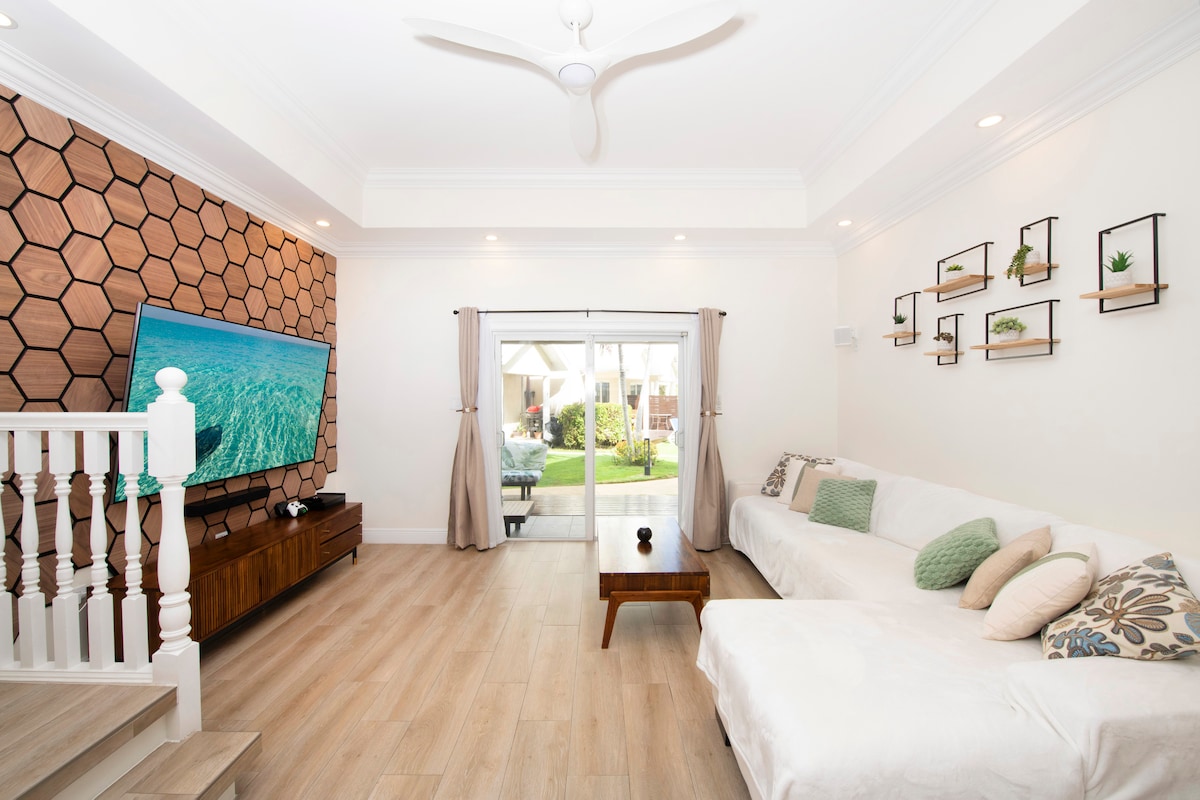 ผ่อนคลายในห้องนั่งเล่นที่อบอุ่นพร้อมโซฟาที่สะดวกสบาย สมาร์ททีวี และการตกแต่งด้วยไม้ที่หรูหรา ประตูบานเลื่อนเปิดออกสู่ลานและสวน - เหมาะสำหรับกาแฟยามเช้าหรือลมเย็น