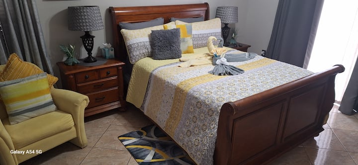 Chumba kikuu cha kulala kilicho na godoro la Queen,
Kiti cha kupumzikia na meza mbili za kuweka vitu.