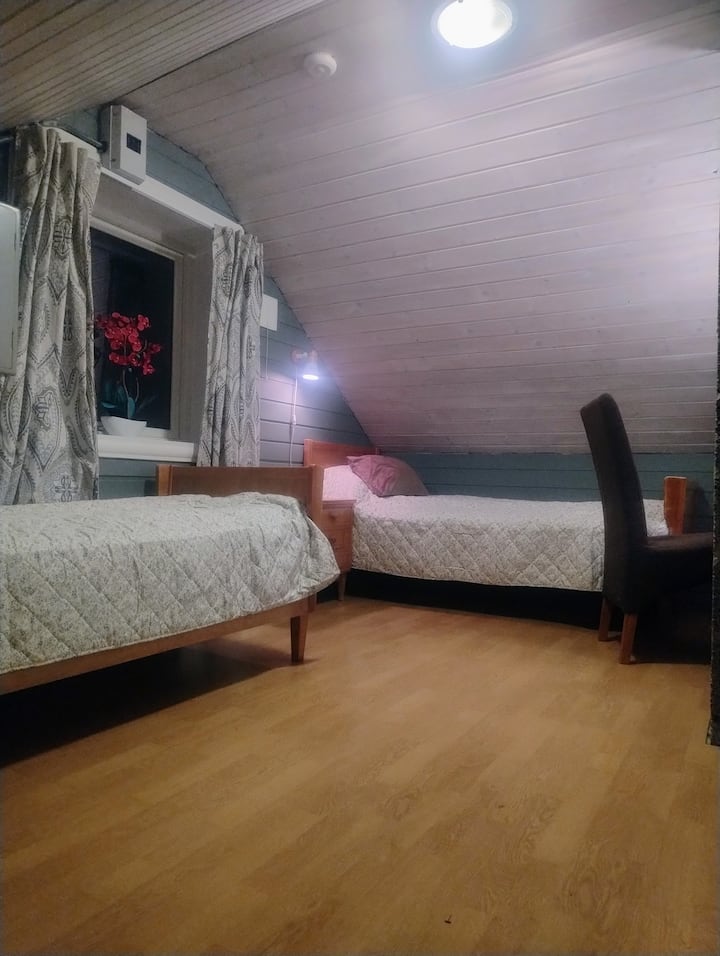 غرفة علوية تحتوي على سريرين ومساحة عمل صغيرة. ممر يؤدي إلى غرفة النوم 2