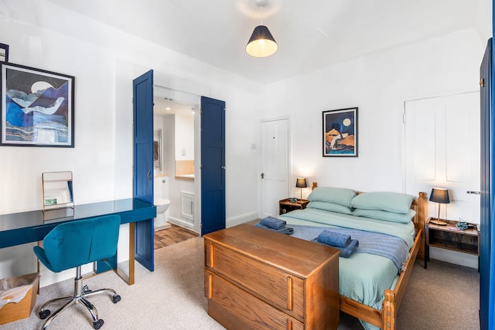 Светла главна спална соба со двоен кревет, биро и многу светлина.
