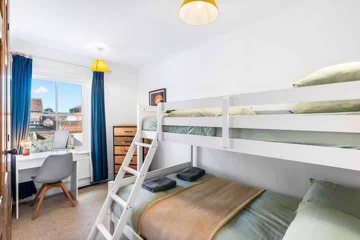 Светла втора спална соба со кревет на спрат, биро и фиоки.