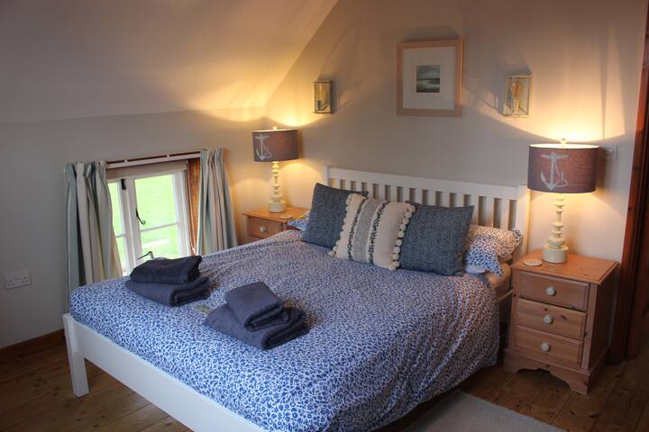 Spacious King size bedroom with vaulted ceiling and exposed beams. 
Chest of drawers.