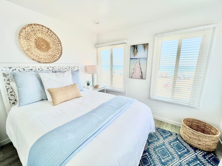 "ห้องนอนชั้นบนมีวิวทะเล เตียงควีนไซส์หรูหรา ผ้าปูที่นอนนุ่มๆ และการตกแต่งสไตล์ชายฝั่งที่สงบ เหมาะสำหรับการพักผ่อนหลังการผจญภัยที่ชายหาด"