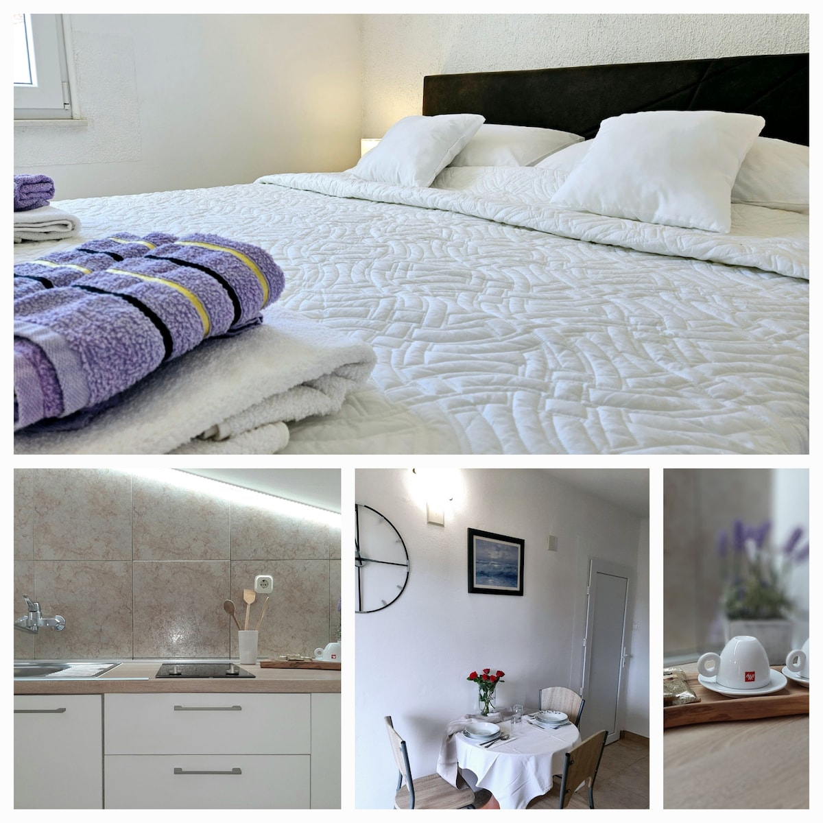 The image showcases a spacious sleeping area, featuring a neatly made bed with white linens and decorative pillows. A set of towels is arranged on the bed's edge. A modern kitchenette is seen in the background, with essential utensils and a clean countertop. An elegantly arranged dining table with flowers and tableware is positioned nearby.