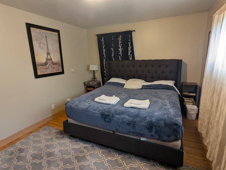 Private bedroom with a king bed, soft linens, natural light, and a calm, comfortable feel. Includes bedside lighting, curtains, rug, and cozy touches for a restful stay.