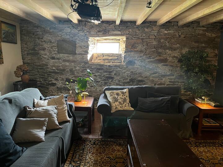 A living room with a projector and a movie screen. The three-seater sofa is a sofa bed.