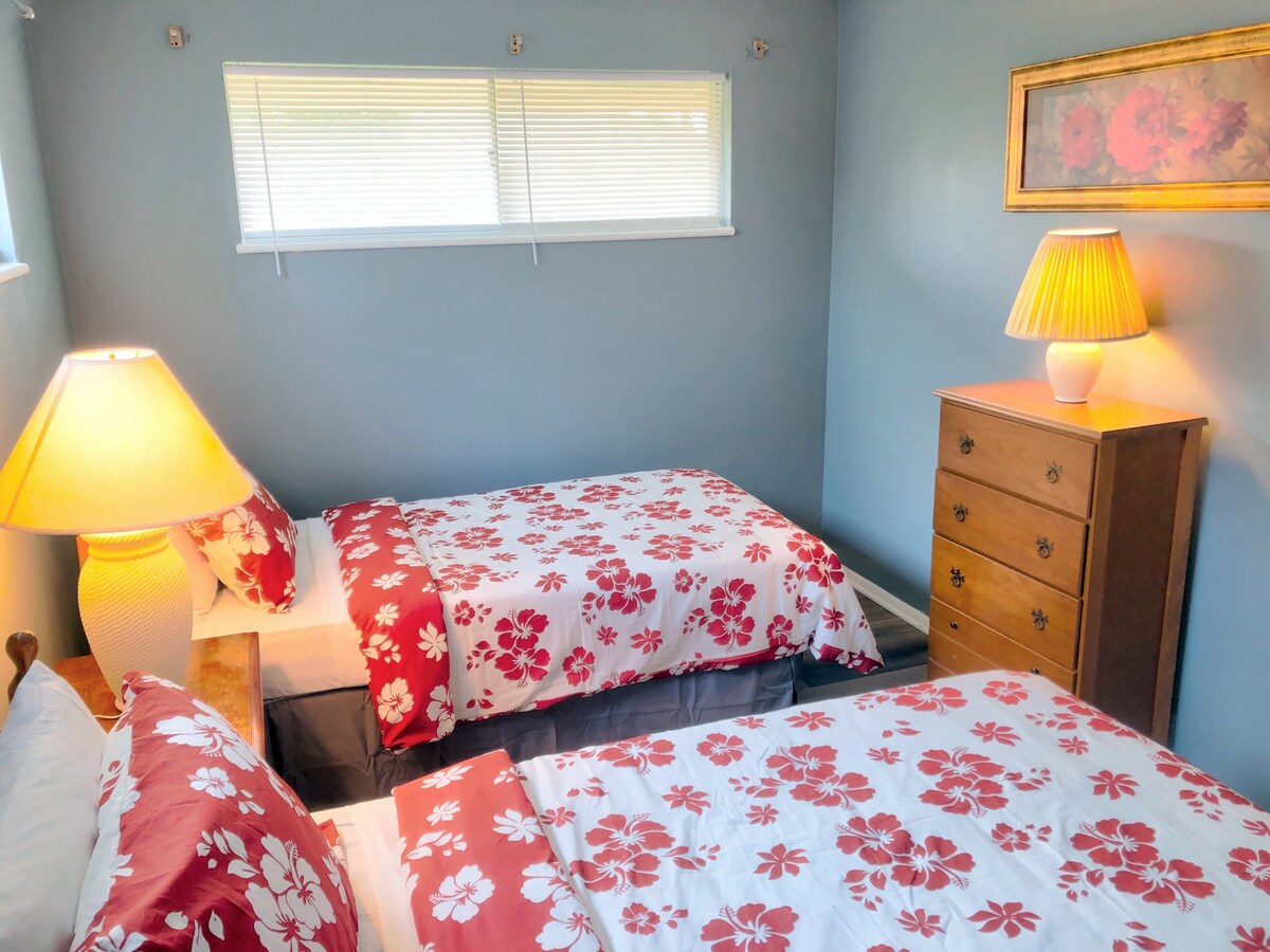 Acogedor dormitorio doble con dos camas cómodas, mesita de noche con lámpara y vestidor.
