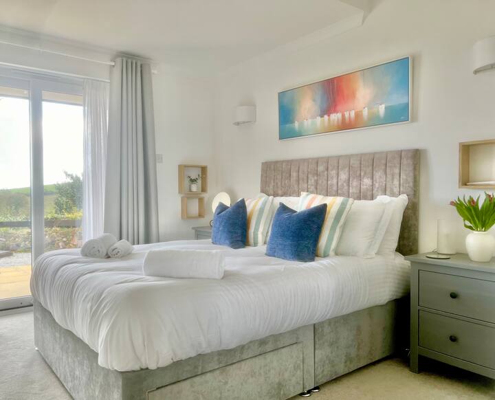 Splendida camera da letto principale con biancheria di lusso e accesso diretto al giardino e viste ininterrotte sul mare e sul sole.