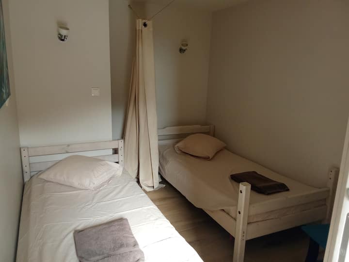 Chambre avec deux lits simples séparés par un rideau