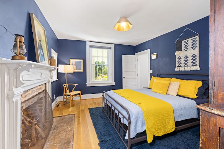 Downstairs primary bedroom w/ queen bed, historic fireplace & wardrobe 