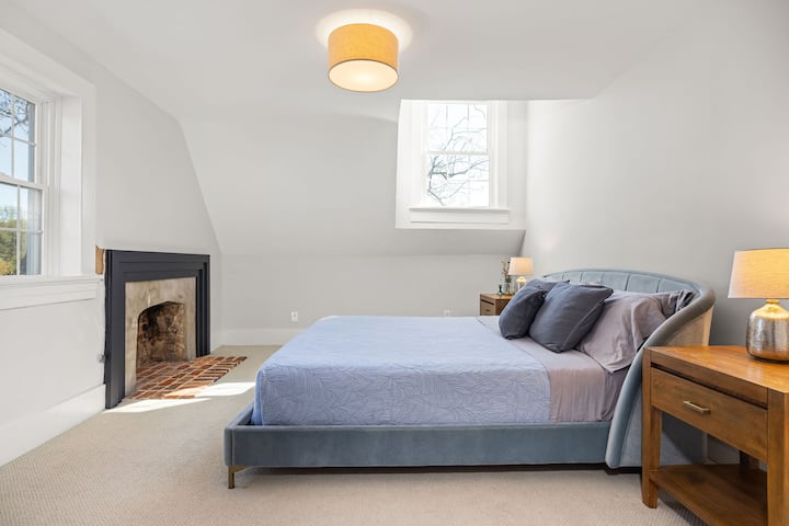 Upstairs bedroom with king bed, historic fireplace, dresser, and closet