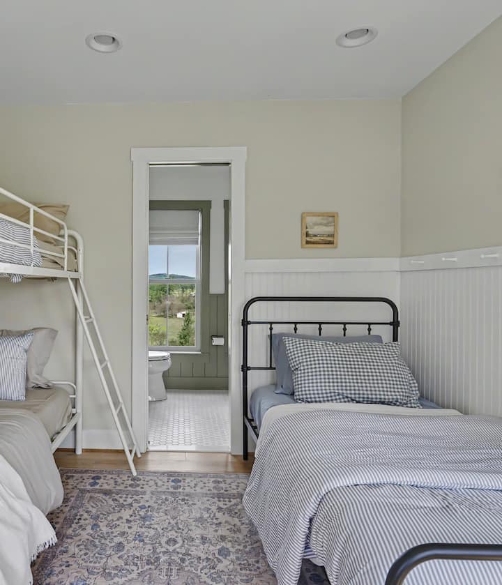 The cutest farmhouse bunk room! This upper bunk room, plus an extra twin bed - sleeps three guests and has high-end luxurious, farmhouse bedding. It features an ensuite bath with amazing views—guests will love the charming white shiplap detail.