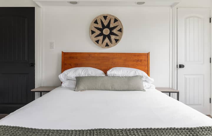 Queen sized bedroom with attached full bath with tub. Over the bed lights, overhead fan, and plenty of storage space including a luggage rack.