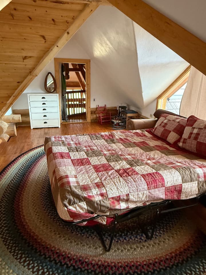 Разтегателен диван с удобен матрак на таванско помещение с изглед към всекидневната