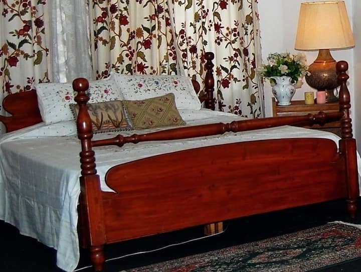King size bed with bed sheets and linen . A side table with a table lamp on both sides of the bed. 