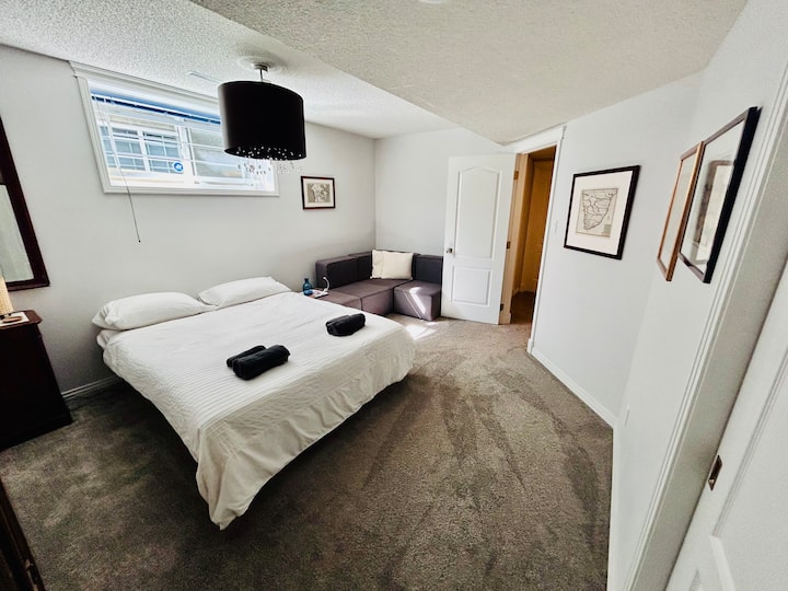 Basement bedroom with a double bed (two single mattresses), closet, and seating area. Technology: outlet with USB port, Sonos speaker.