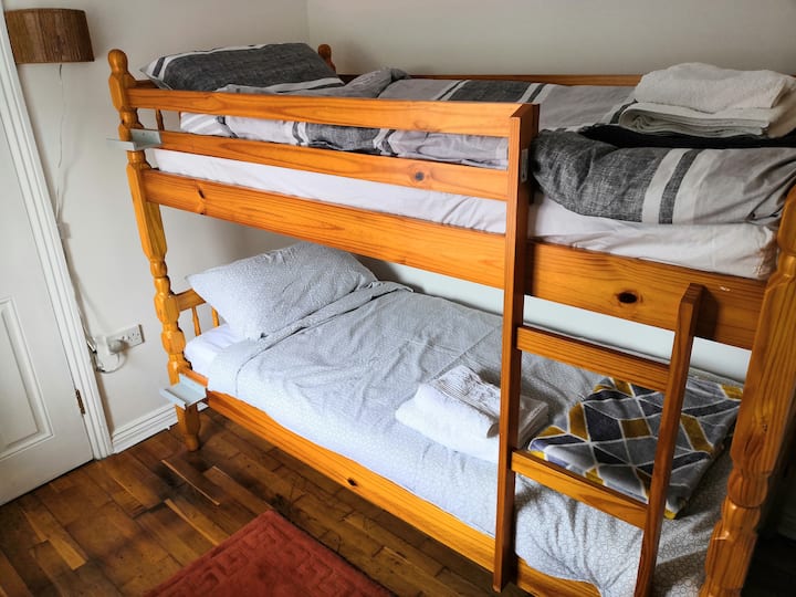 Kitanda cha ghorofa kilicho na ngazi ya pembeni, taa iliyowekwa ukutani iliyo na swichi ya pamoja na dirisha kubwa ambalo linajaza chumba mwanga wa asili.