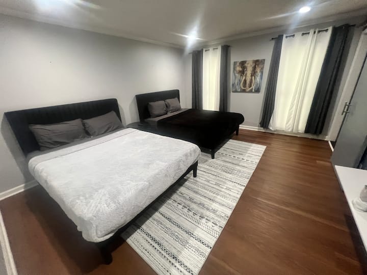 Front bedroom with two queen beds, bright crisp white walls, and hardwood floors, ideal for siblings, friends, or family traveling together.