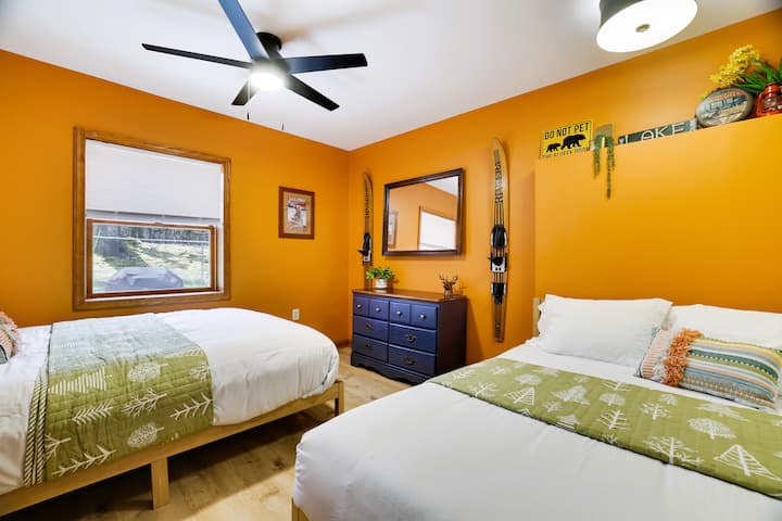 Camp themed guest room with Queen & Double beds, ceiling fan, and back yard wooded views