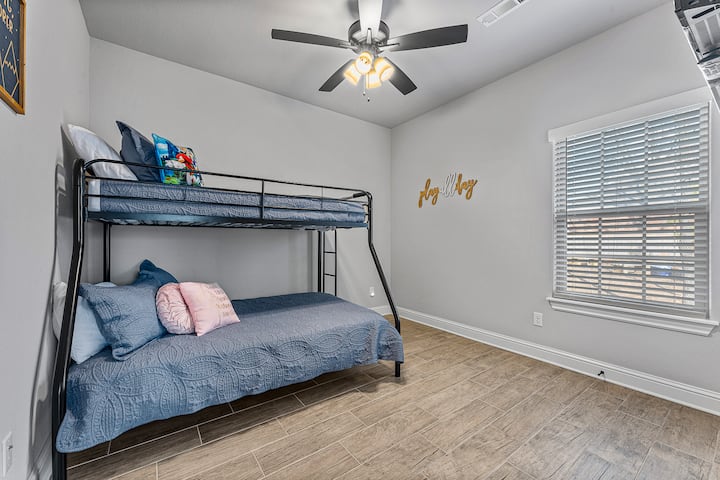 Dormitorio con litera con cama doble, ventilador de techo, pisos de baldosas de aspecto de madera y luz natural, ideal para familias o grupos.