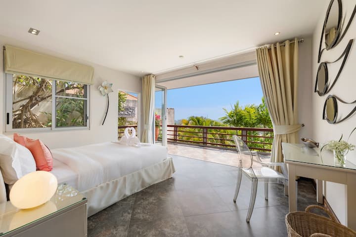Sube a las verdes vistas al jardín desde la comodidad de una cama tamaño queen, enmarcada por una gran ventana plegable que invita a la brisa del mar a tu sereno y elegante santuario.