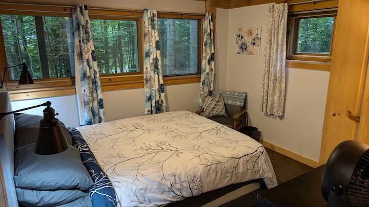 This bedroom has a queen bed with a chair, a closet, and a dresser.