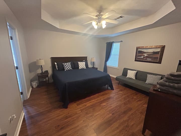 Large primary bedroom with futon, TV, and NO CARPET!