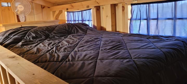 The upstairs sleeping loft has a bed, pillows, extra blankets and a fan.