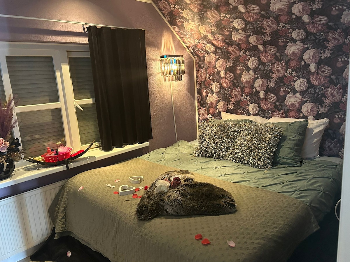 Sfeervolle slaapkamer met een opgemaakt kingsize bed, warme verlichting en een tv met gratis Netflix en Google Chromecast.
Bij aankomst liggen er handdoeken klaar (1 grote en 1 kleine p.p.).
Optioneel is romantische aankleding mogelijk.
 