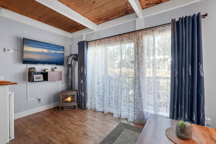 غرفة معيشة بها باب منزلق كبير وموقد - خفيفة وجيدة التهوية وجذابة.