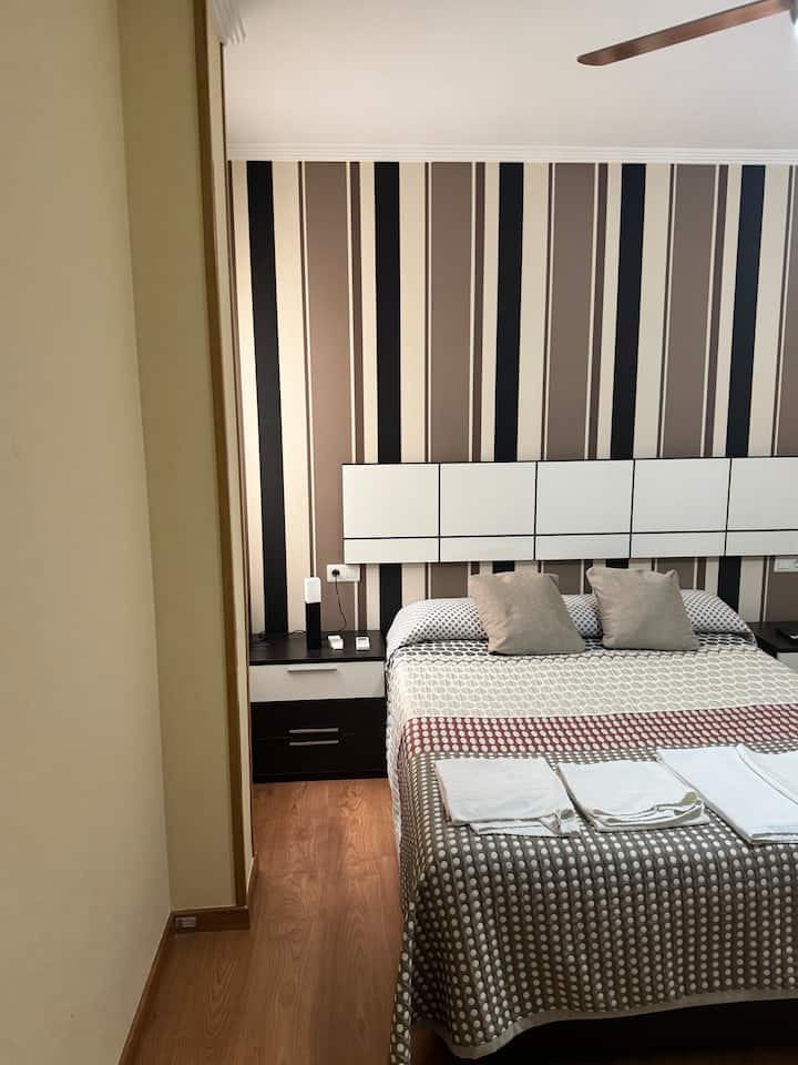 Dormitorio 3 con cabecero moderno, mesillas y toallas preparadas.