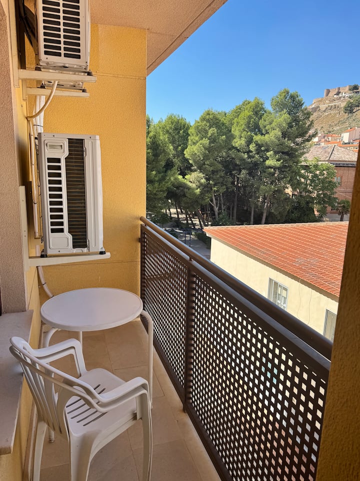 Balcón con mesita y sillas: un café al aire libre con vistas al pueblo.
