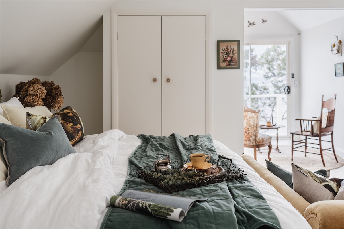 ห้องนอนใหญ่มีเตียงขนาดคิงไซส์พร้อมผ้าปูที่นอนน่ารักๆและห้องนั่งเล่นเล็กๆที่มองออกไปยังริมน้ำ 