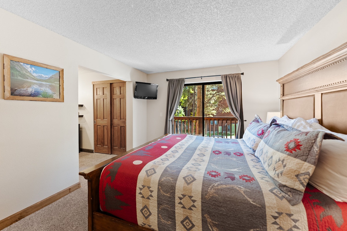 Primary bedroom featuring a king-sized bed, mounted TV, and en suite bathroom. 