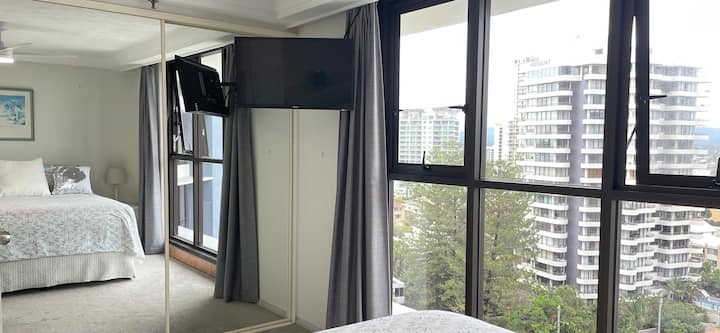 A bright queen bedroom with mirrored wardrobes, TV and relaxed river and hinterland outlook.