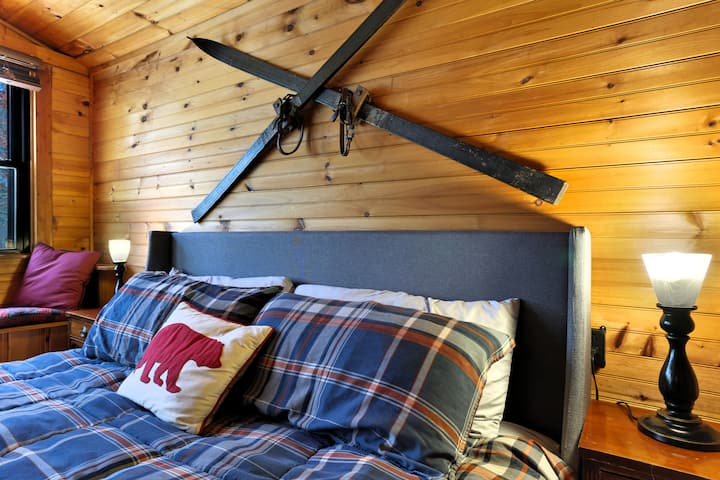 Acogedor dormitorio en cabaña con ropa de cama a cuadros y decoración de esquí vintage