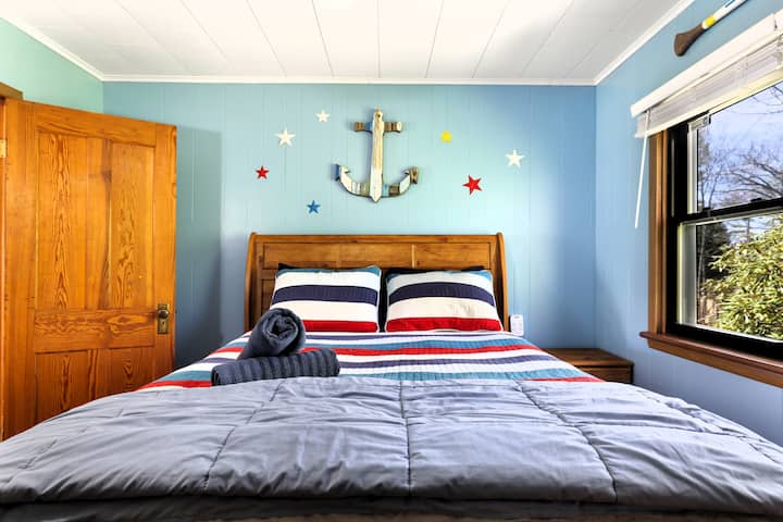 Habitación náutica soleada con una cama acogedora, toallas limpias y vistas al jardín.