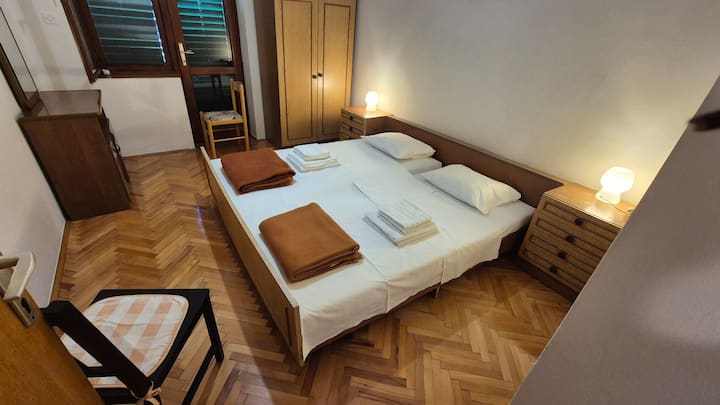 Druhá spálňa na prvom poschodí s dverami na spoločný balkón. Posteľ je veľká ako manželská posteľ pre dvoch.