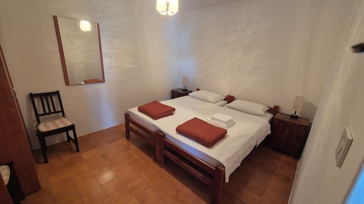 Spálňa na prízemí s dvoma oddelenými posteľami. Izba má pracovný stôl a šatník.