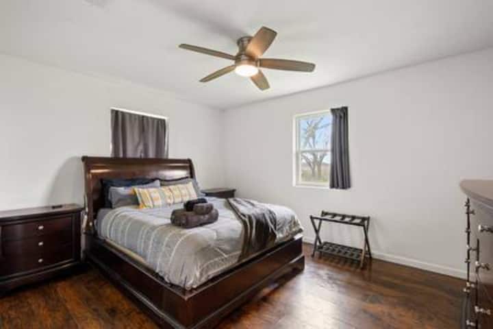 Rest peacefully in your comfortable bedroom featuring dark wood furnishings, ceiling fan, and natural light streaming through the window.   (no TV)