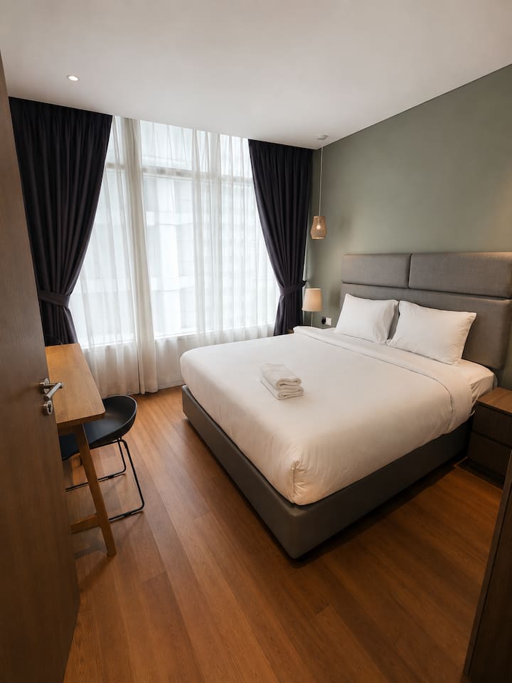 Deuxième chambre confortable avec un lit Kind-size, des draps moelleux et des baies vitrées offrant une lumière naturelle au Vortex KLCC.