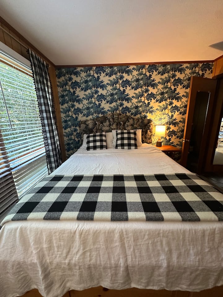 Queen bed in the main floor bedroom. Attractive custom wallpaper and headboard.