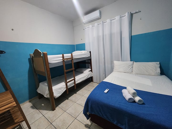 Bedroom with a double bed, bunk bed, towels and bedding, air conditioning, lockable closet, clothes rack, hangers, and a bathroom outside the bedroom.