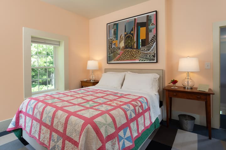 Bedroom on the second floor has windows on three sides, original art, and heirloom quilts. Reading lamps!