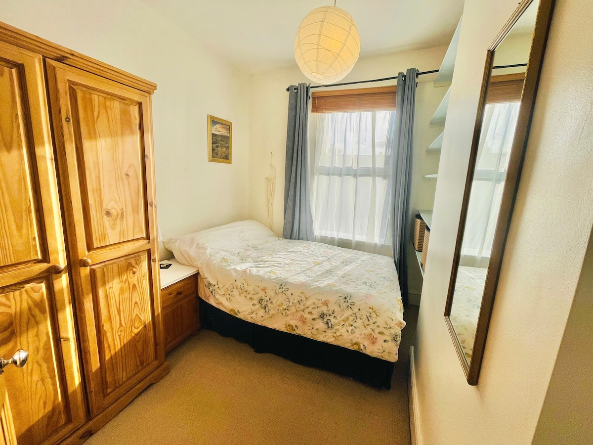 Chumba kidogo cha kulala mara mbili kinachopokea jua la alasiri.